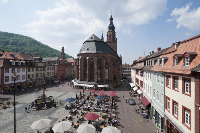 Der alte  Marktplatz von Heidelberg zwischen Rathaus und Heiliggeistkirche. In der Mitte erinnert der  1706 und 1709 errichtete Herkulesbrunnen an den Wiederaufbau der Stadt nach den m Pfälzischen Erbfolgekrieg.